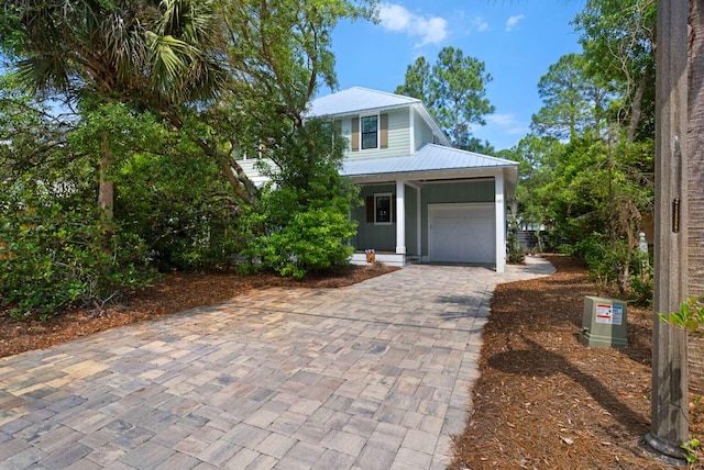 161 Lakewood Dr, Santa Rosa Beach, FL 32459 - view of front of house with decorative driveway, an attached garage, metal roof, and a porch
