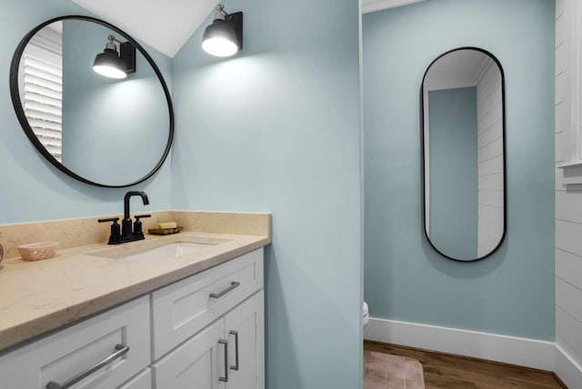 161 Lakewood Dr, Santa Rosa Beach, FL 32459 - bathroom featuring wood finished floors, vanity, baseboards, lofted ceiling, and toilet