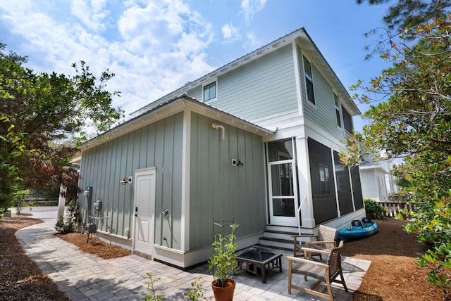 161 Lakewood Dr, Santa Rosa Beach, FL 32459 - rear view of property featuring a patio area, a sunroom, board and batten siding, entry steps, and a fire pit