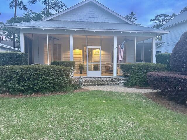 384 Carson Oaks Ln, Santa Rosa Beach, FL 32459 - view of front of property featuring ceiling fan, a sunroom, a front yard, and metal roof