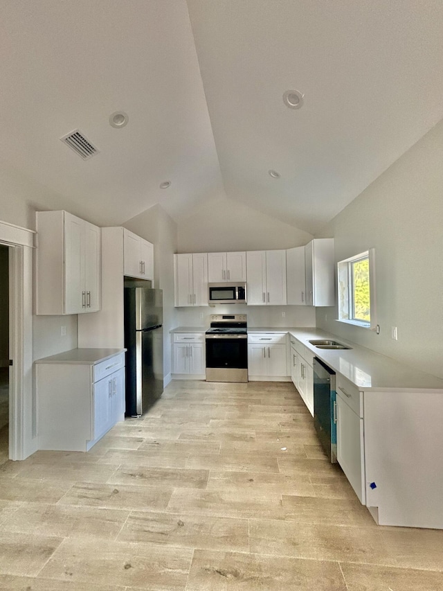 LOT11 E Georgie Pt, Washington, FL 32459 - kitchen with stainless steel appliances, vaulted ceiling, a sink, light wood-style floors, and white cabinetry