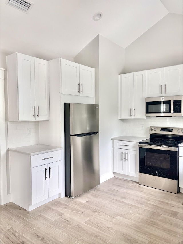 LOT11 E Georgie Pt, Washington, FL 32459 - kitchen with appliances with stainless steel finishes, light countertops, white cabinets, decorative backsplash, and high vaulted ceiling