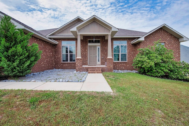 view of front of property with brick siding, board and batten siding, a shingled roof, and a front yard