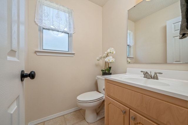 half bath with toilet, vanity, tile patterned floors, and baseboards