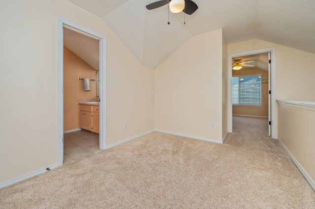 bonus room featuring lofted ceiling, light colored carpet, baseboards, a textured ceiling, and ceiling fan