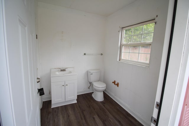 bathroom featuring baseboards, wood finished floors, toilet, and vanity