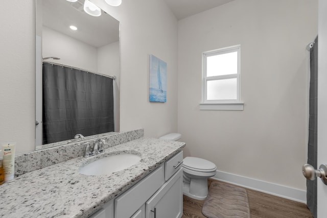 full bath featuring wood finished floors, vanity, curtained shower, baseboards, and toilet