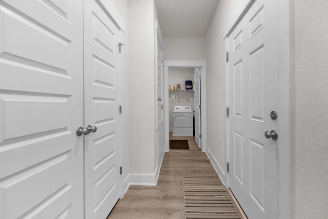 hallway featuring baseboards, washer / clothes dryer, and light wood-style floors