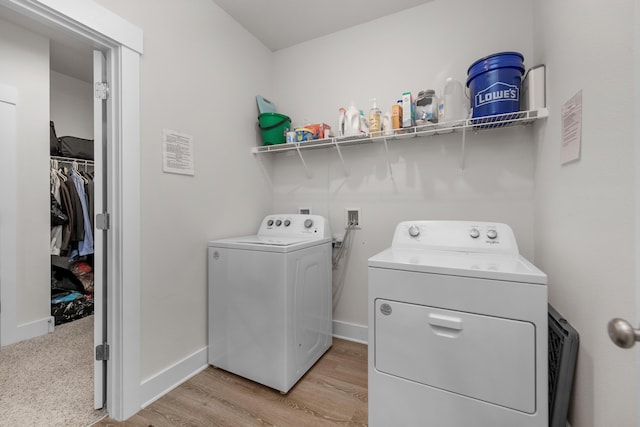clothes washing area featuring washing machine and dryer, baseboards, light wood finished floors, and laundry area