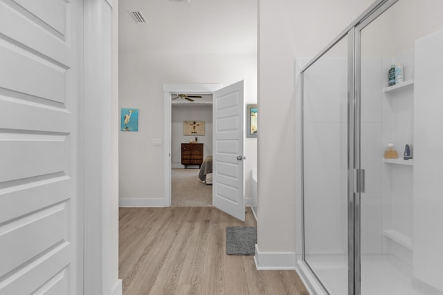 ensuite bathroom featuring visible vents, a ceiling fan, wood finished floors, and a stall shower