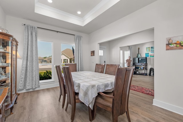 dining room featuring recessed lighting, light wood-type flooring, baseboards, and a tray ceiling