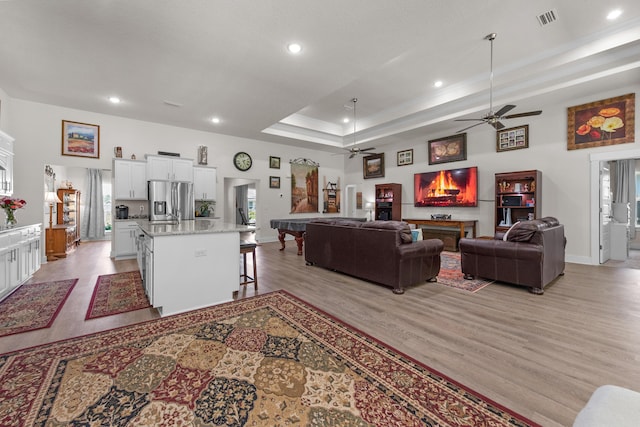 living area with a ceiling fan, light wood finished floors, baseboards, visible vents, and recessed lighting