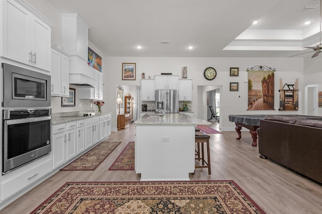 kitchen featuring open floor plan, appliances with stainless steel finishes, light wood-style floors, and white cabinetry