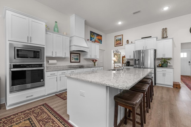 kitchen with white cabinets, wood finished floors, stainless steel appliances, and visible vents