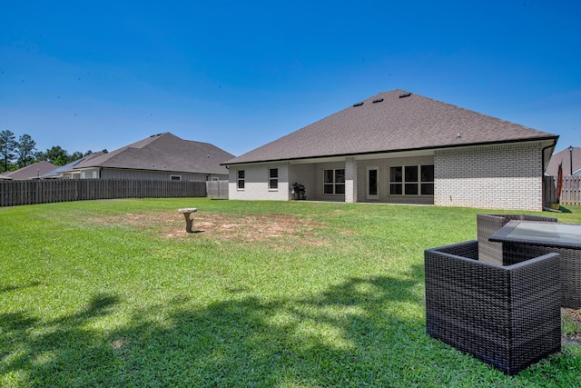 rear view of house with a lawn, a fenced backyard, and brick siding