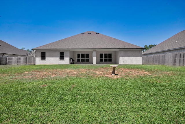 back of property featuring brick siding, a yard, and fence