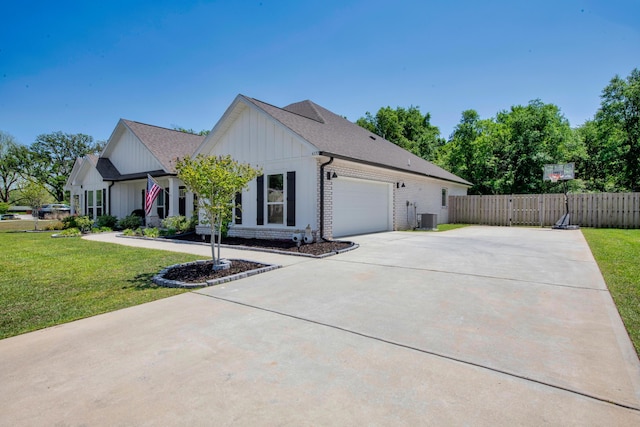 view of side of property with a lawn, driveway, an attached garage, fence, and cooling unit