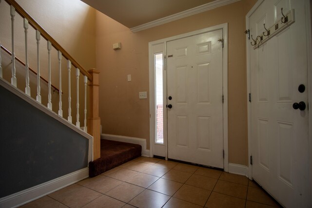 entryway featuring tile patterned floors, stairs, baseboards, and crown molding