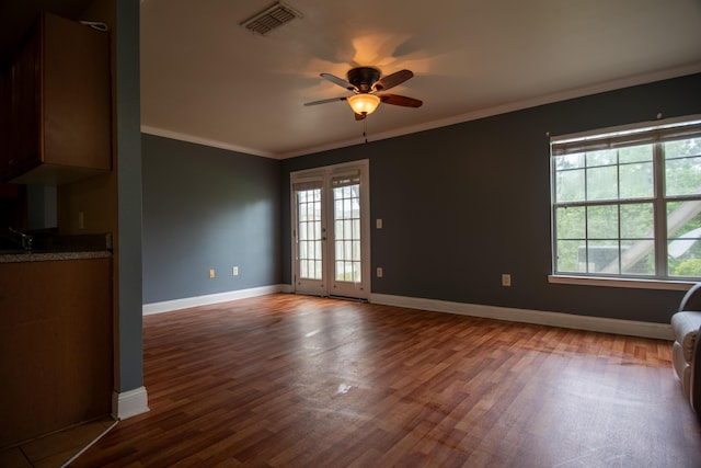 unfurnished living room featuring baseboards, a ceiling fan, crown molding, visible vents, and wood finished floors