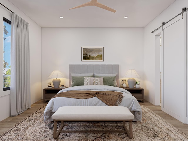 bedroom with recessed lighting, a barn door, ceiling fan, and light wood-type flooring