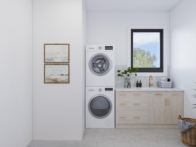 laundry room featuring a sink, cabinet space, and stacked washer / drying machine