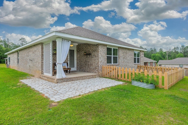 back of house with brick siding, fence, and a yard