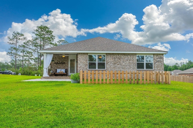 view of front facade with brick siding, fence, a shingled roof, and a front yard