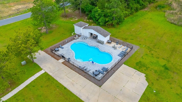 view of swimming pool featuring fence, a fenced in pool, an outdoor structure, a yard, and a patio