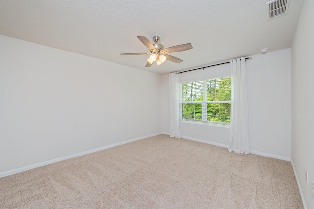 carpeted spare room featuring visible vents, baseboards, and ceiling fan