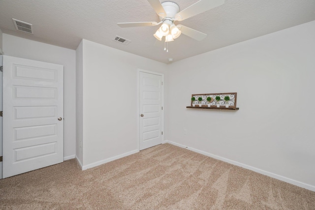 empty room with carpet floors, baseboards, visible vents, and ceiling fan