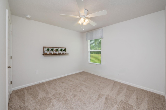 carpeted spare room featuring baseboards and ceiling fan