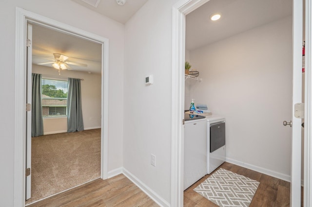 laundry room with a ceiling fan, laundry area, washing machine and dryer, and wood finished floors