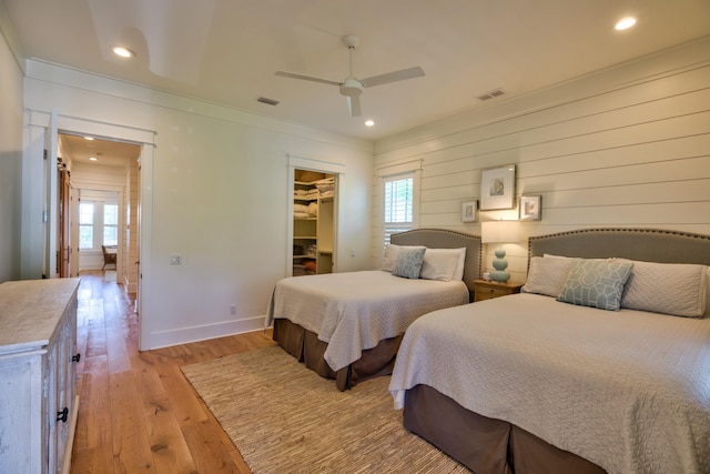 bedroom with a spacious closet, light wood-type flooring, visible vents, and multiple windows