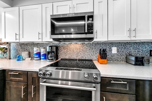 kitchen with white cabinetry, stainless steel appliances, light stone counters, and tasteful backsplash