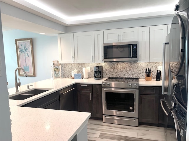 kitchen with white cabinets, tasteful backsplash, a sink, and stainless steel appliances