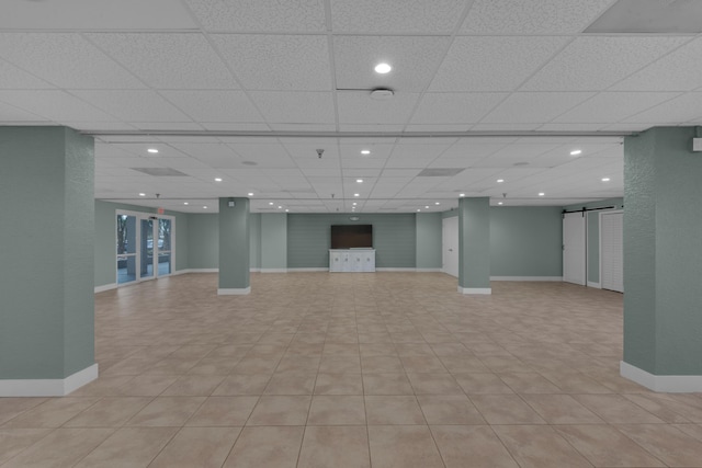 below grade area featuring baseboards, a barn door, and recessed lighting