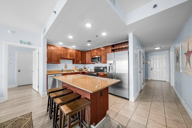 9860 S Thomas Dr Unit 501, Panama City Beach, FL 32408 - kitchen featuring a sink, a kitchen island, light stone countertops, a kitchen breakfast bar, and appliances with stainless steel finishes