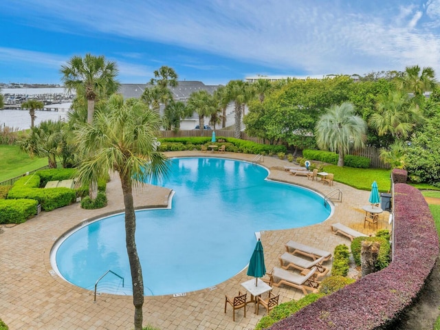 community pool with a patio area and fence