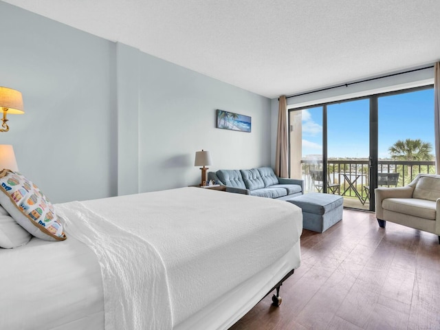 bedroom with a wall of windows, wood finished floors, access to exterior, and a textured ceiling