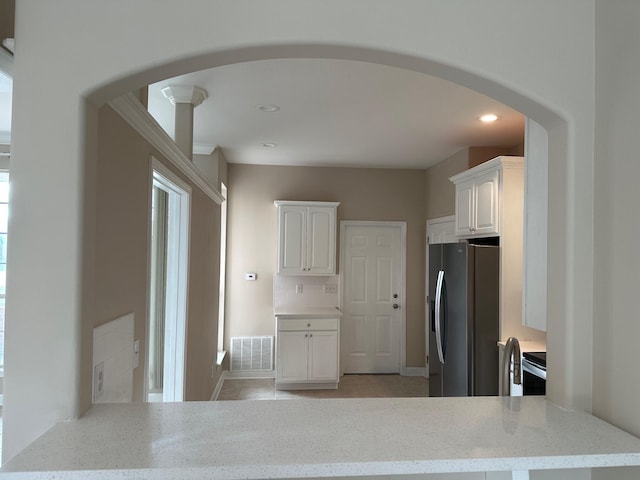 287 Stahlman Ave, Destin, FL 32541 - kitchen with arched walkways, white cabinets, stainless steel fridge, and light stone countertops