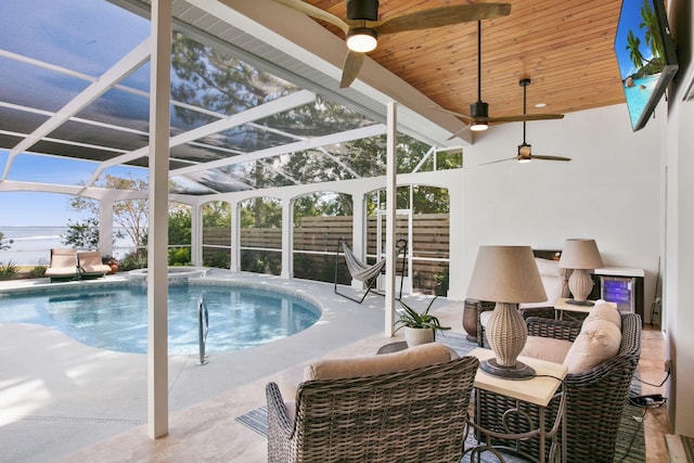 view of pool with glass enclosure, fence, a patio, and a ceiling fan