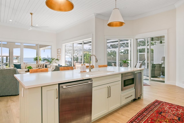 kitchen with light countertops, light wood-style floors, ornamental molding, and appliances with stainless steel finishes