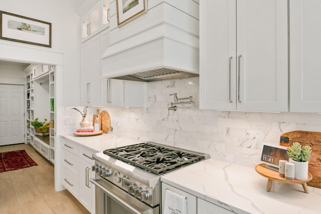 kitchen featuring premium range hood, white cabinetry, tasteful backsplash, and stainless steel stove