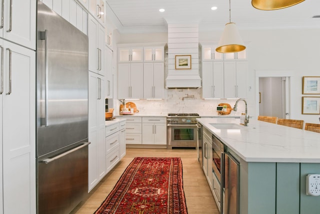 kitchen featuring ornamental molding, a sink, premium appliances, and white cabinets
