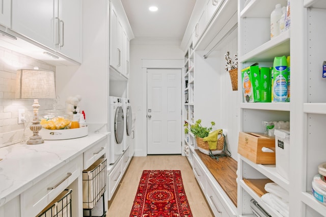 laundry area featuring light wood-type flooring, washing machine and clothes dryer, cabinet space, and ornamental molding