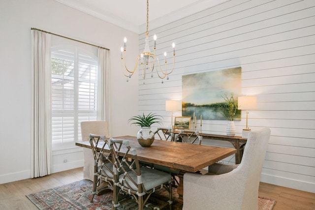 dining room featuring light wood-style flooring, a notable chandelier, crown molding, and baseboards