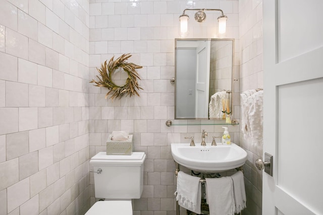 bathroom with tile walls, tasteful backsplash, toilet, and a sink