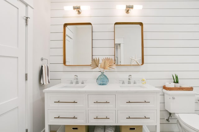full bath with double vanity, a sink, and toilet