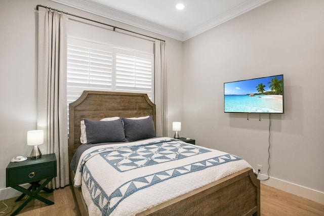 bedroom with ornamental molding, baseboards, and wood finished floors