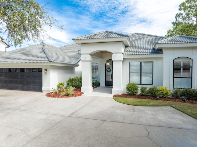 view of front of home with stucco siding, an attached garage, a tiled roof, and concrete driveway